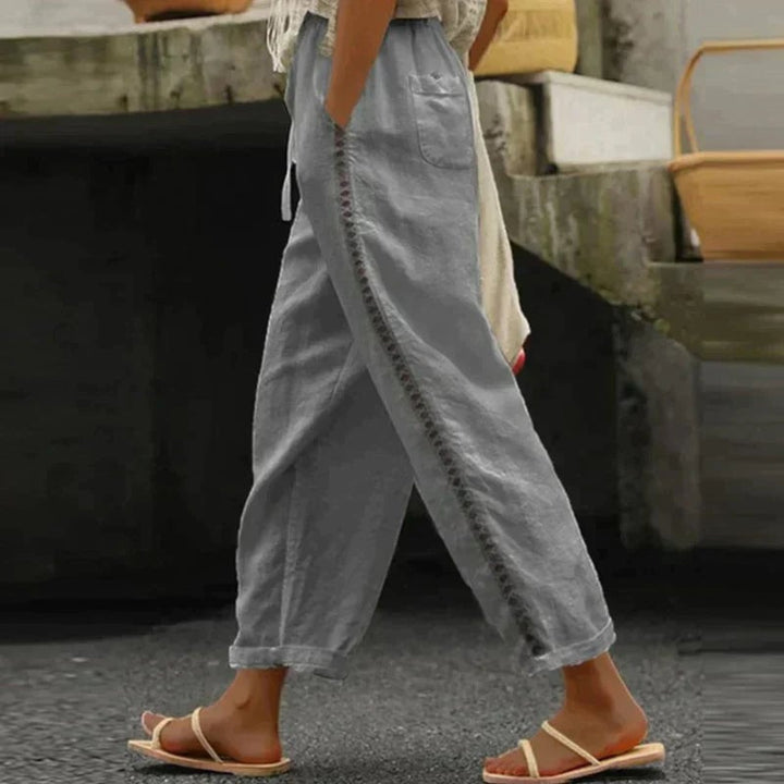 Close-up of contrast button side stripe detail on Abby tapered trousers in white