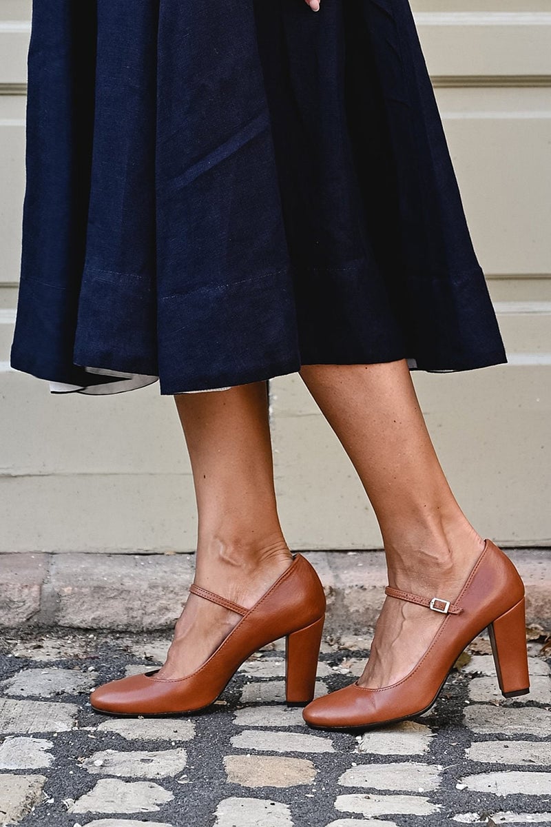 Ainsley brown sandals styled on feet with a flowy midi dress on a light background