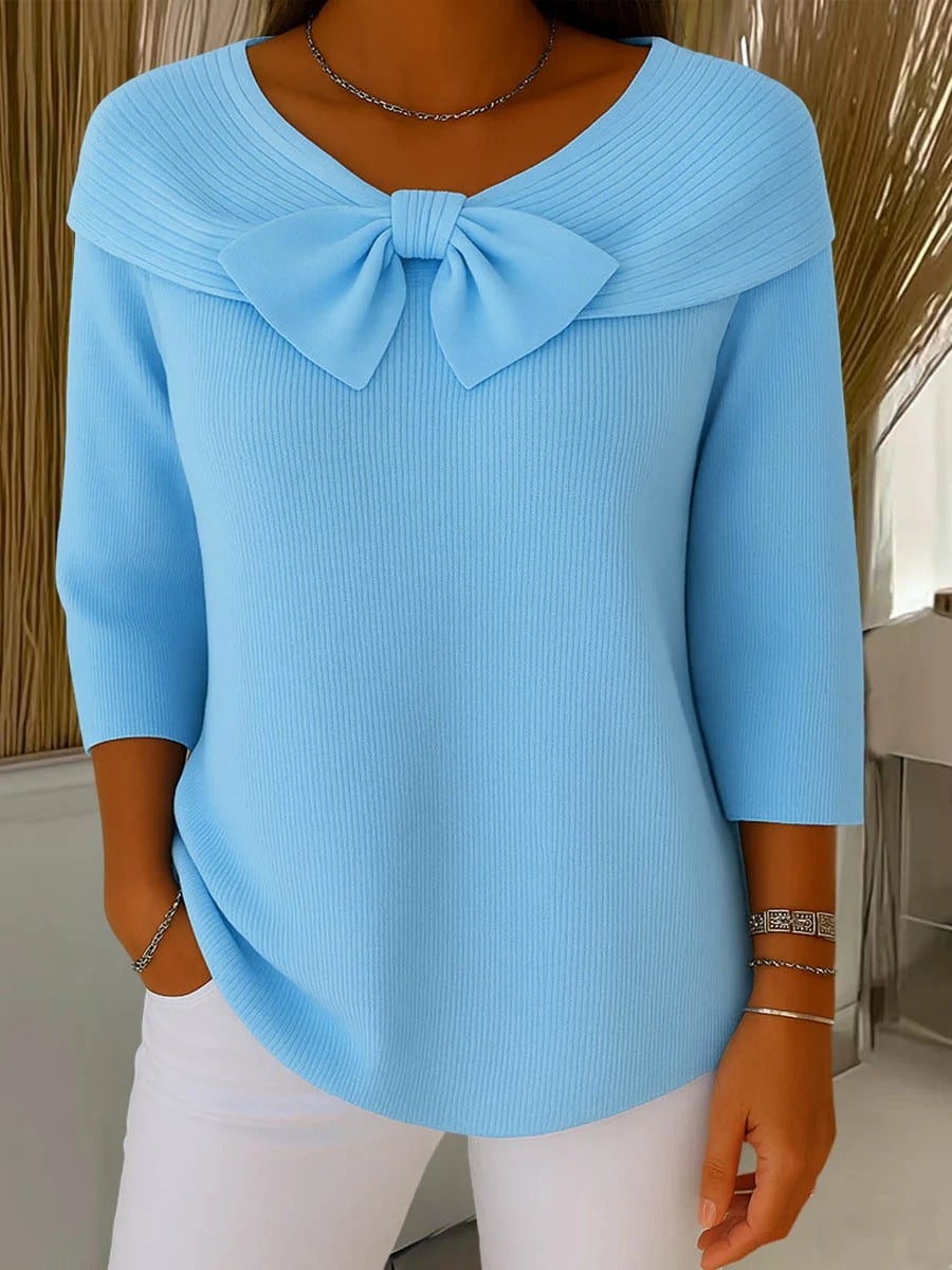 Woman wearing a soft knit sweater with a delicate bow at the round neckline in blue