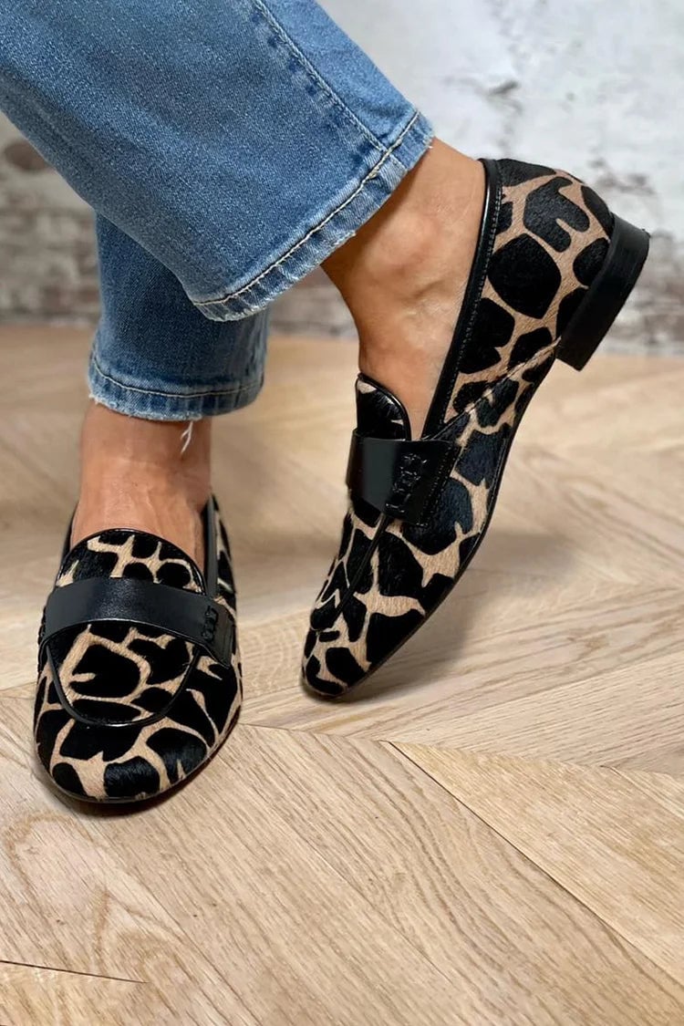Black and white cow print loafers shown from a three-quarter angle on a clean background