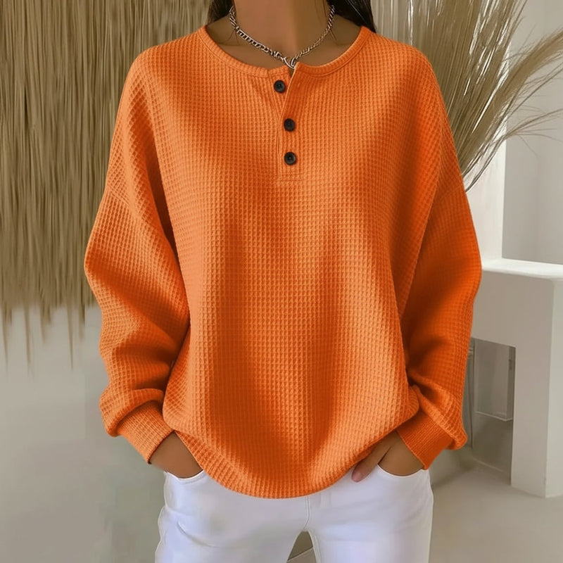 Woman wearing the Alexa cozy waffle sweater in orange with a relaxed fit and textured knit detail