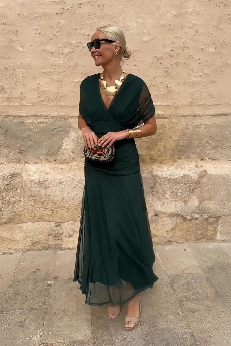 Model wearing a green V-neck pleated maxi dress with a flowing skirt, front view