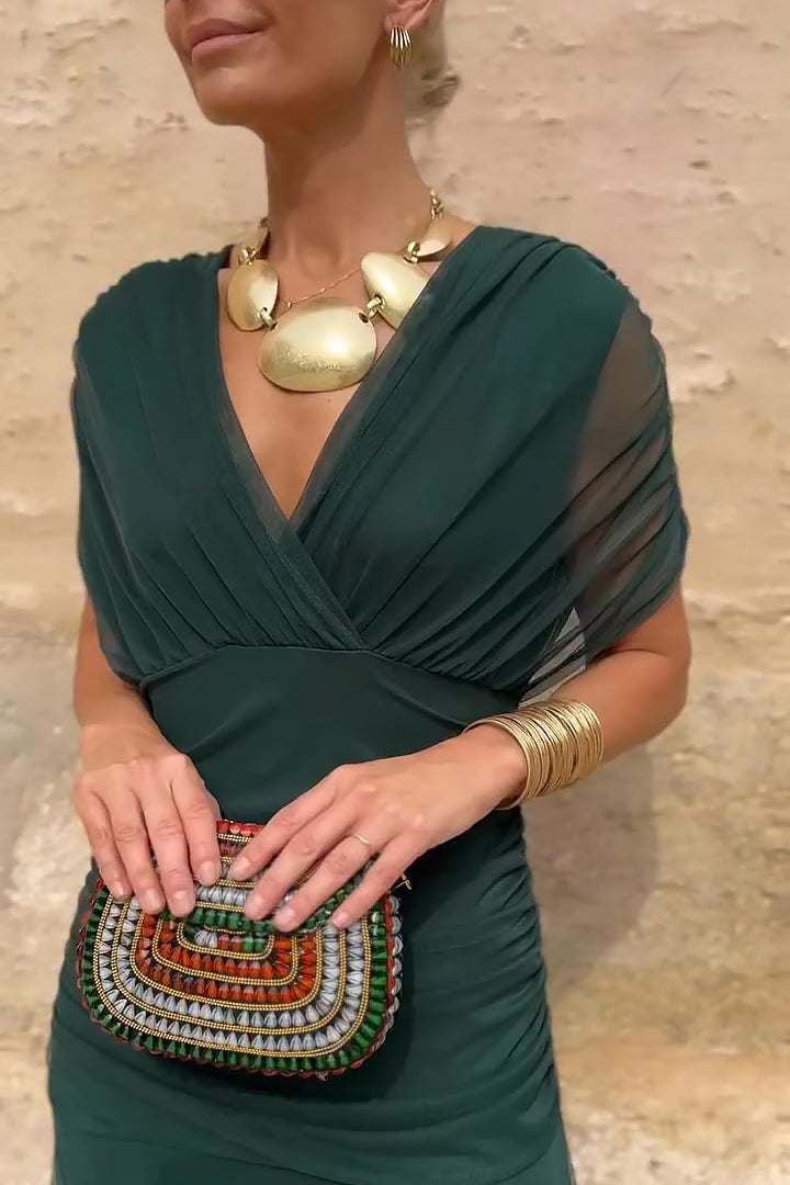 Model in a green V-neck maxi dress shown from the side highlighting the flowing silhouette