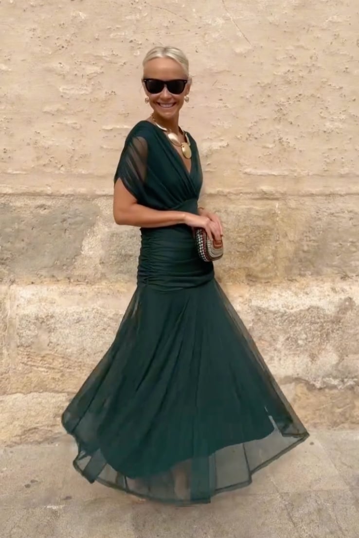 Model posing in a green party maxi dress against a soft background