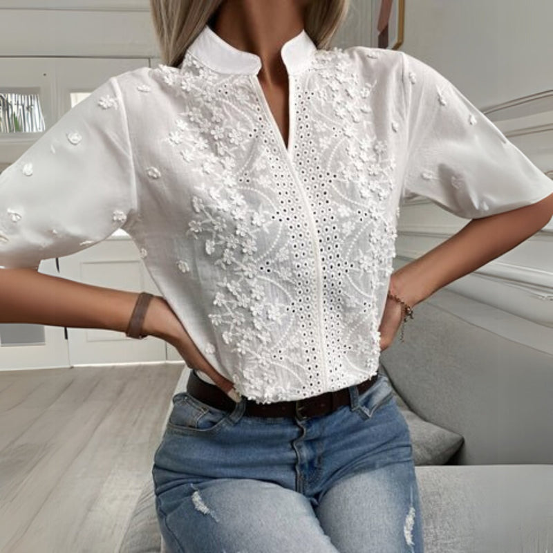 Close-up of delicate floral embroidery and cutout details on white blouse