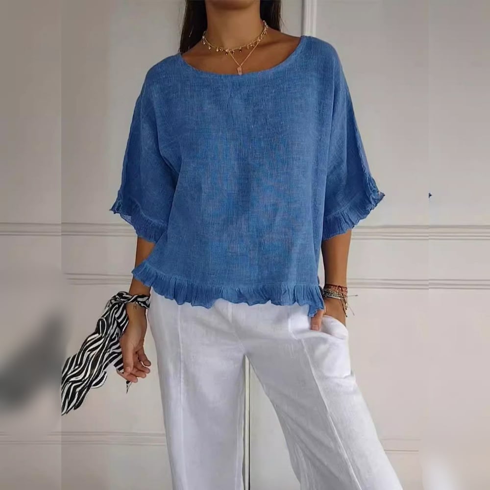 Woman wearing a soft blue ruffle-hem blouse with delicate sleeve details, styled for a casual elegant look