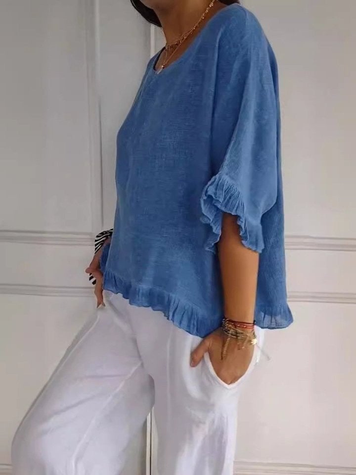 Close-up of ruffle sleeve and hem detail on a lightweight flowing blouse in soft blue