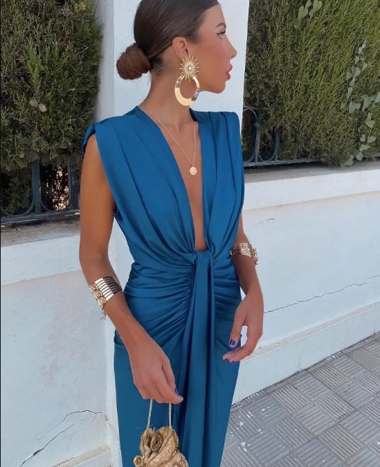 Model wearing the Amelia Soft Pleated Midi Dress in orange, showing the flowy silhouette and vertical pleats