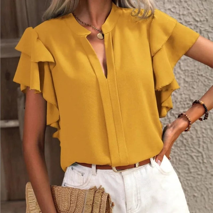 Side profile of model in the Amira ruffle blouse highlighting the draped silhouette and feminine sleeve detail