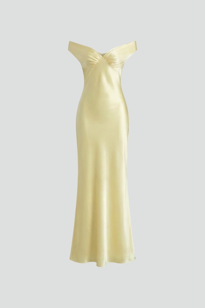 Woman wearing a yellow off shoulder fitted maxi dress with ruched bodice and floor-length hemline