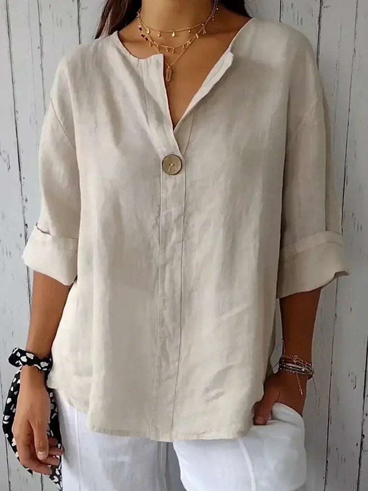 Model wearing a relaxed casual V-neck blouse with a single-button detail in a neutral beige color