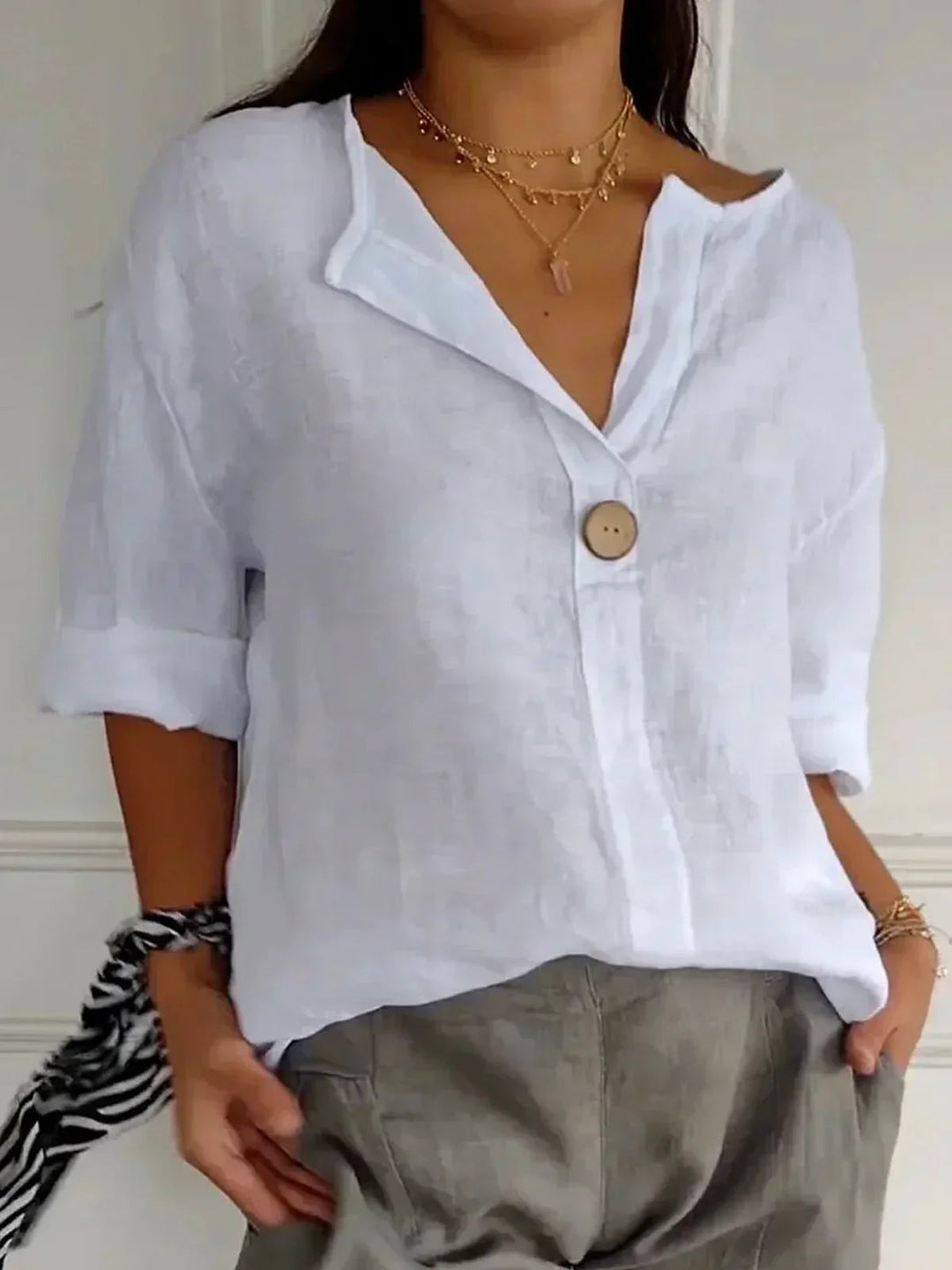 Model wearing the Angela casual V-neck blouse in red, paired with tailored trousers