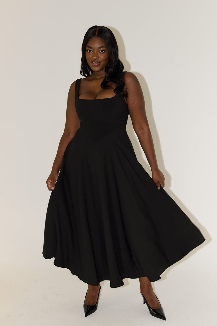 Model wearing the flowy black midi dress, highlighting the midi-length hem