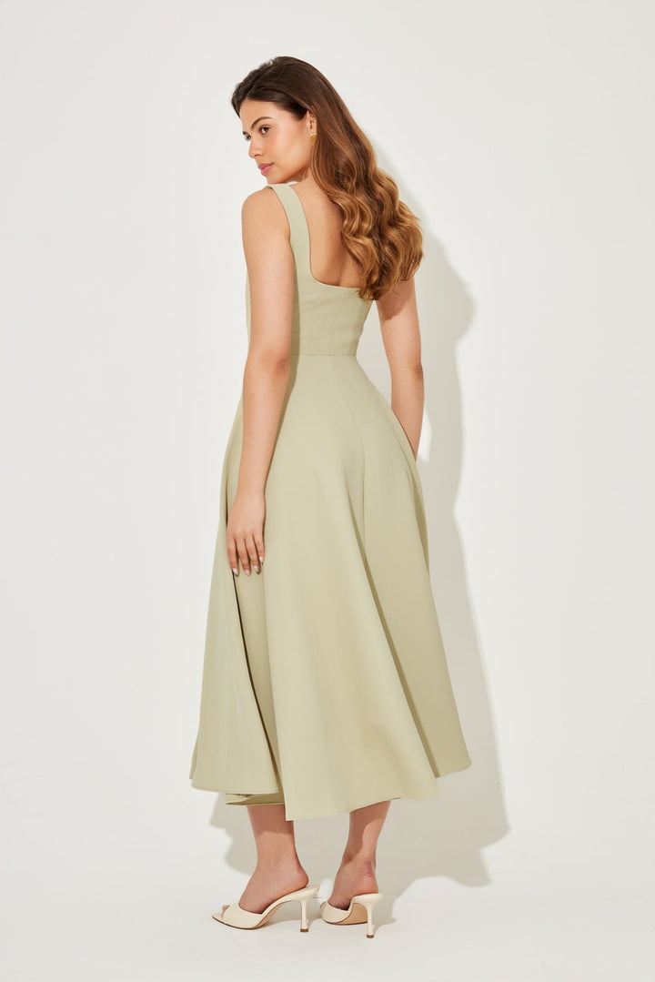 Model smiling in the white flowy midi dress, styled with heels