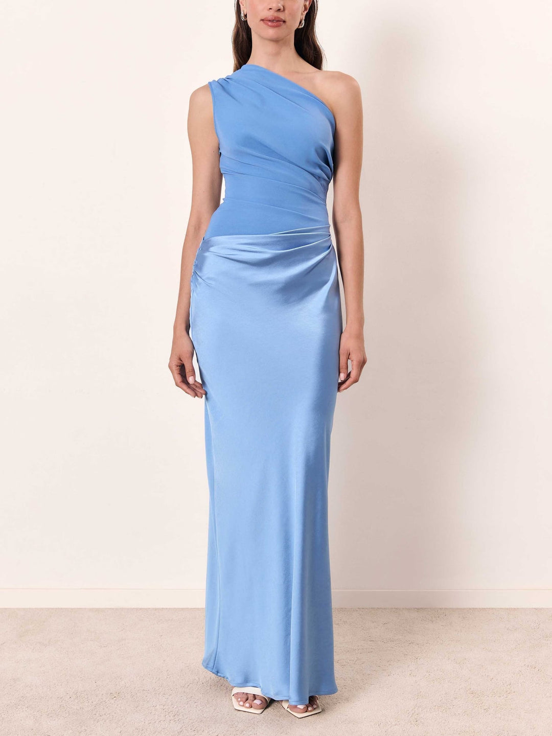 Model posing in a dark green one-shoulder pleated maxi dress for a formal occasion