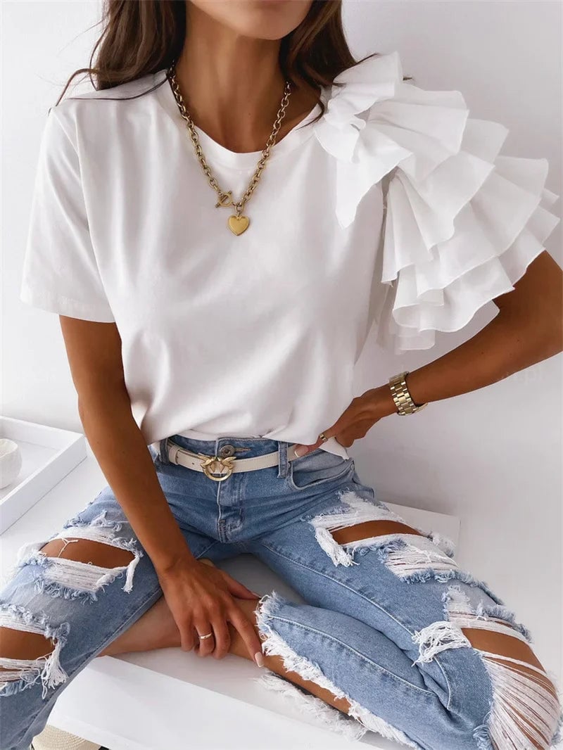 Woman in a black ruffle sleeve statement top paired with fitted pants for an evening look