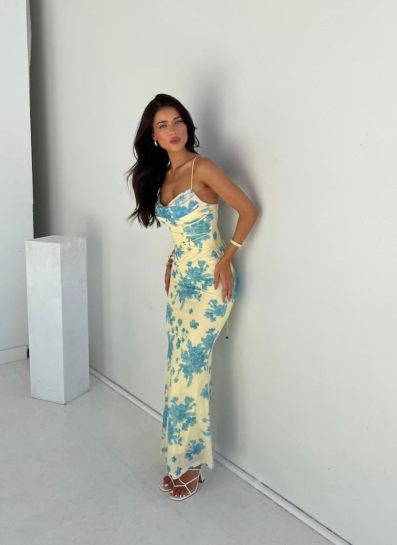 Woman wearing the Annabelle yellow and blue floral sleeveless maxi dress at an outdoor summer event