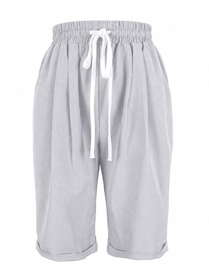 Woman styling dark gray capri pants with white sneakers and a relaxed tee