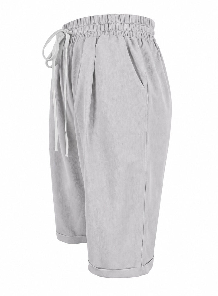 Overhead flat lay of capri pants in three colors: blue, dark gray, and gray