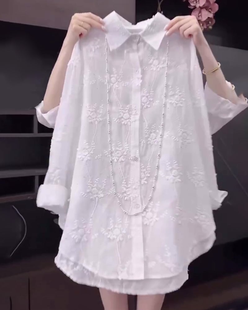Woman wearing a white loose-fit floral embroidered dropped-shoulder shirt, front view