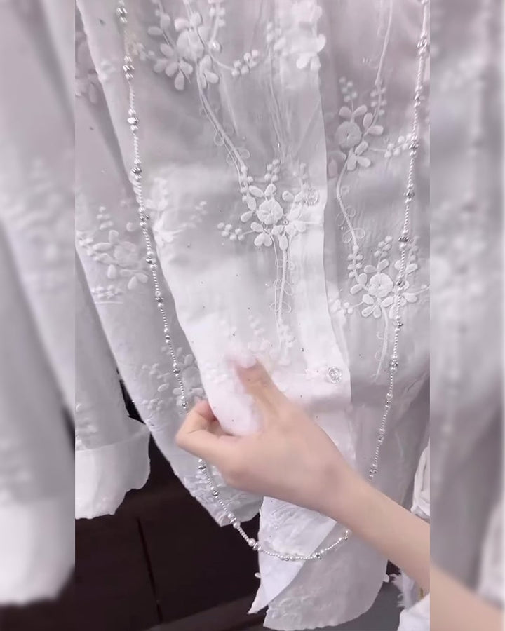 Side view of a relaxed white embroidered shirt with dropped-shoulder silhouette