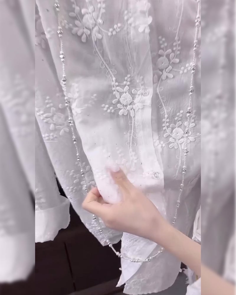 Side view of a relaxed white embroidered shirt with dropped-shoulder silhouette