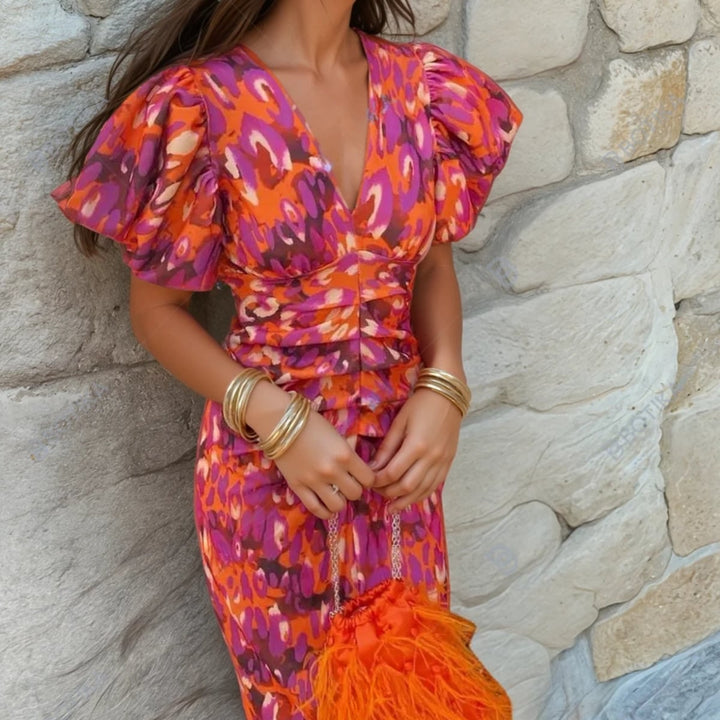 Woman wearing the Aria vibrant printed dress in orange with a flowing silhouette and flattering waist detail