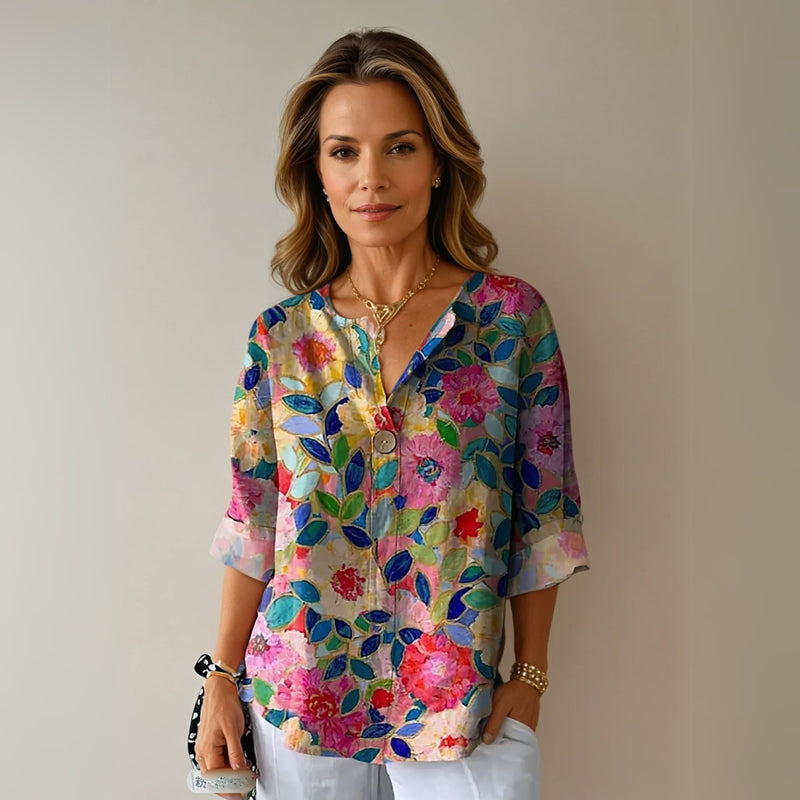 Model wearing the Arlene floral print blouse in blue and pink tones, styled with tailored trousers