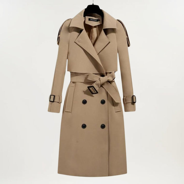 Model in a black longline trench coat with deep pockets and adjustable belt, front-facing pose