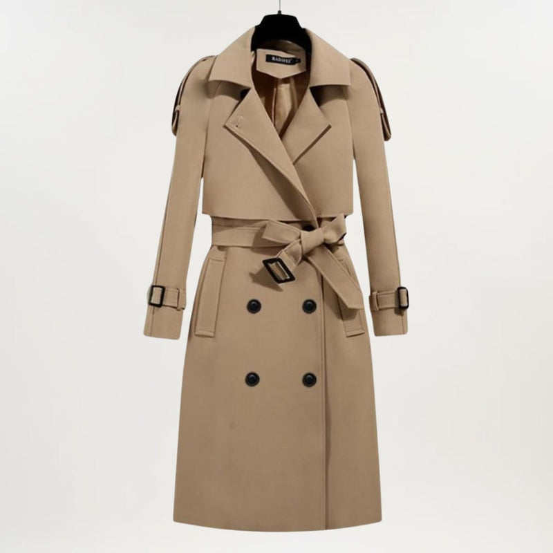 Model in a black longline trench coat with deep pockets and adjustable belt, front-facing pose