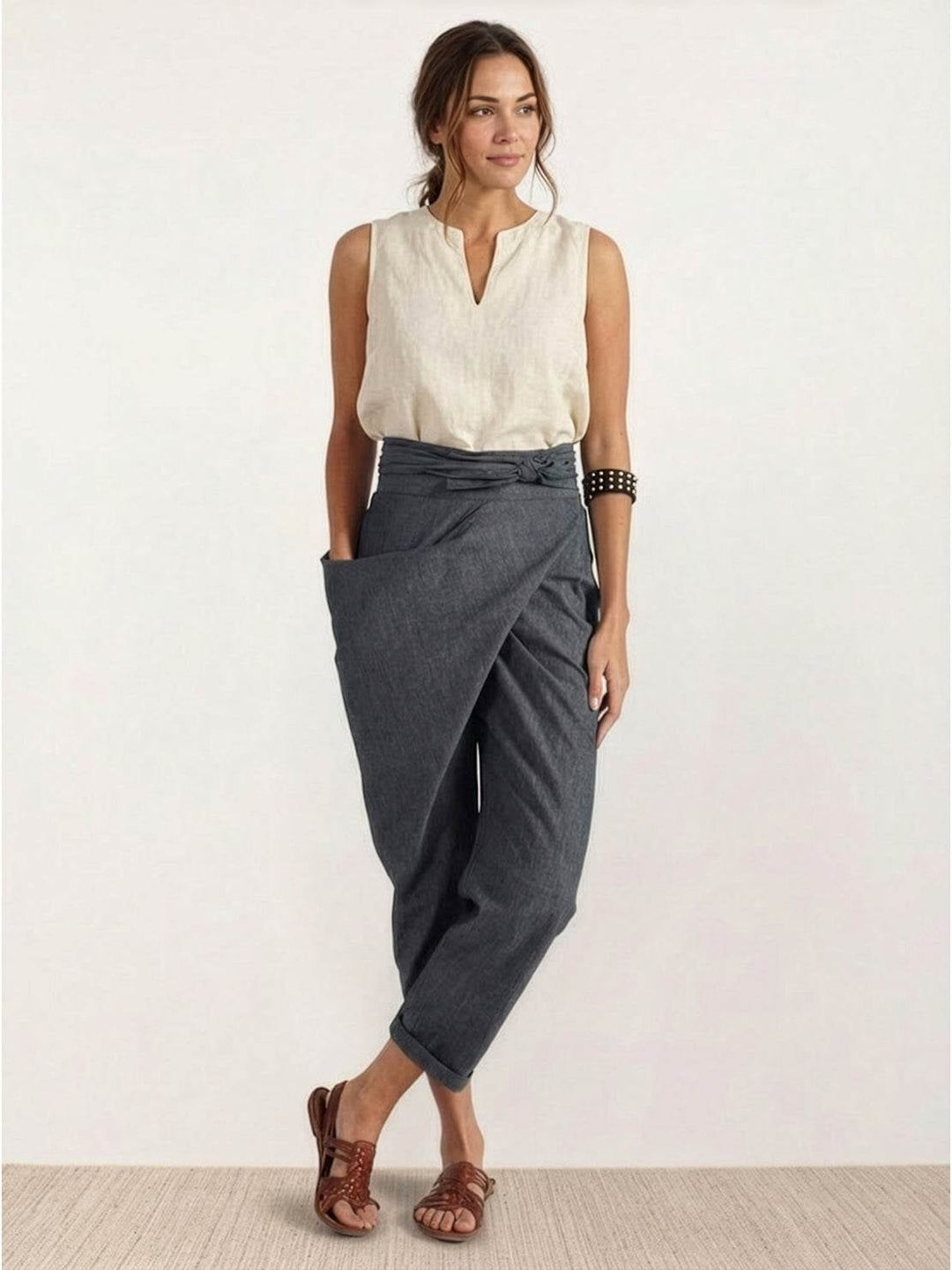 Model wearing gray wrap front tapered pants with a fitted white tank top