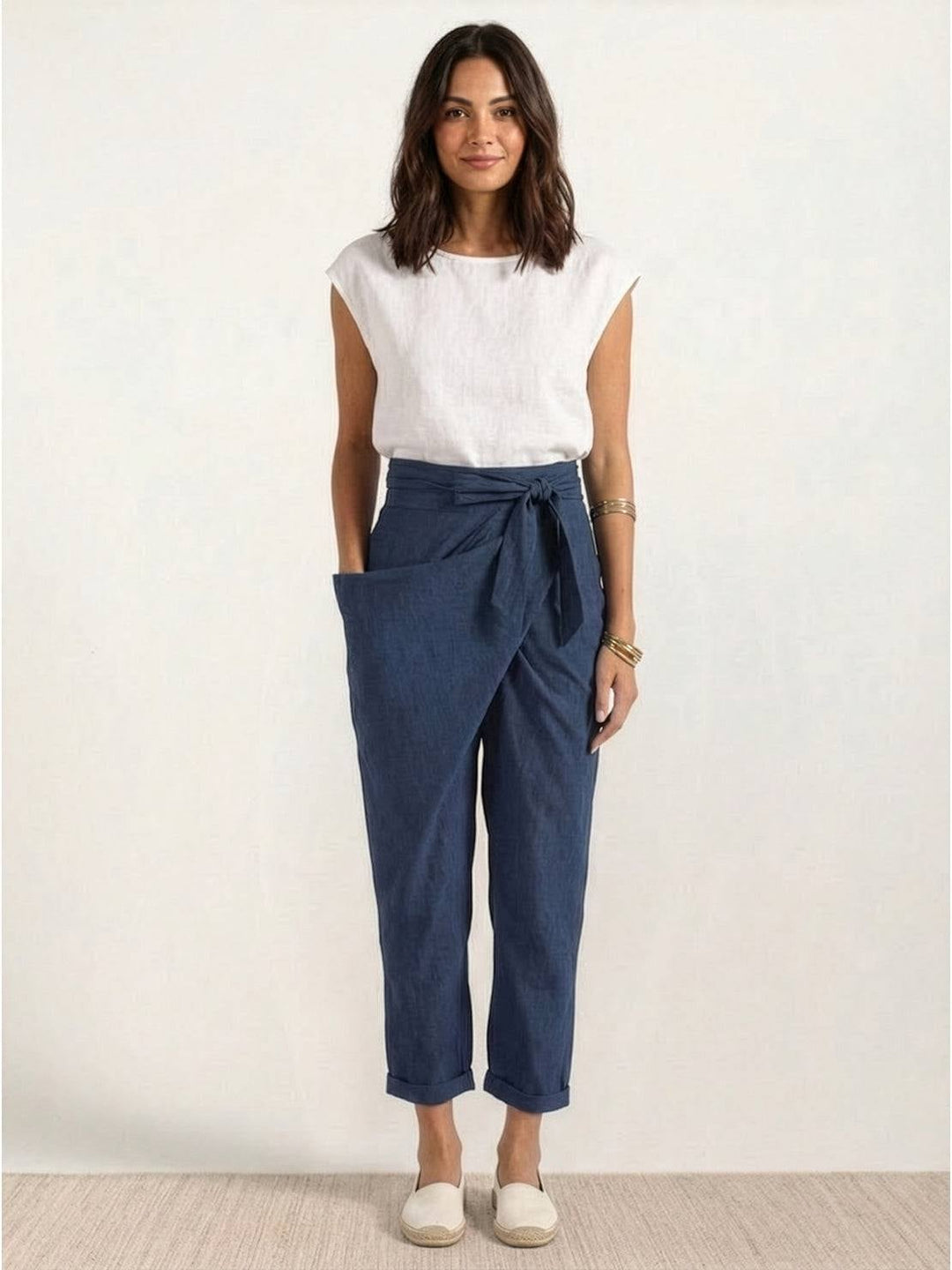 Model wearing navy blue wrap front pants with a tucked-in blouse