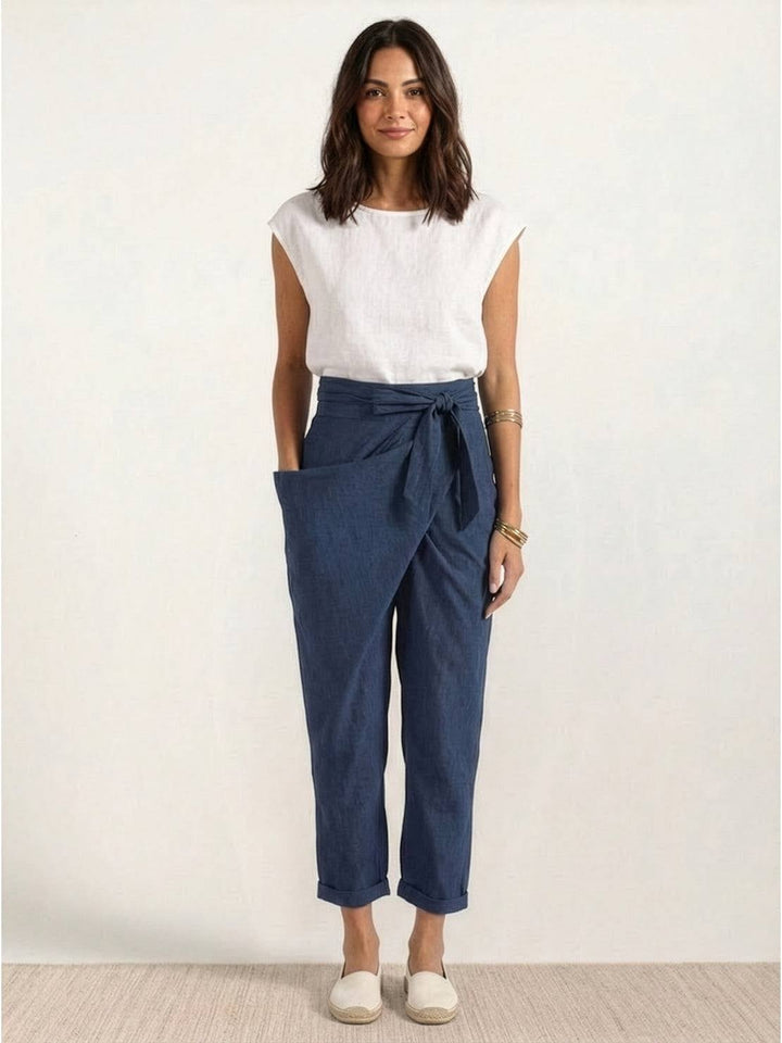 Model wearing navy blue wrap front pants with a tucked-in blouse