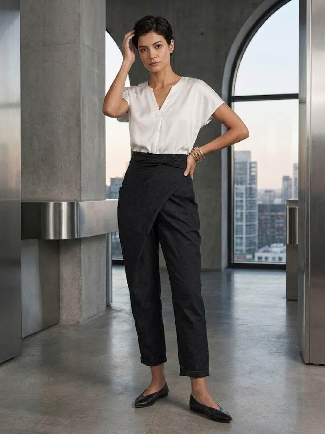 Side view of black wrap front tapered pants with rolled cuff