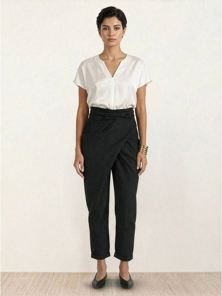 Model wearing black wrap front tapered pants with slip-on mules
