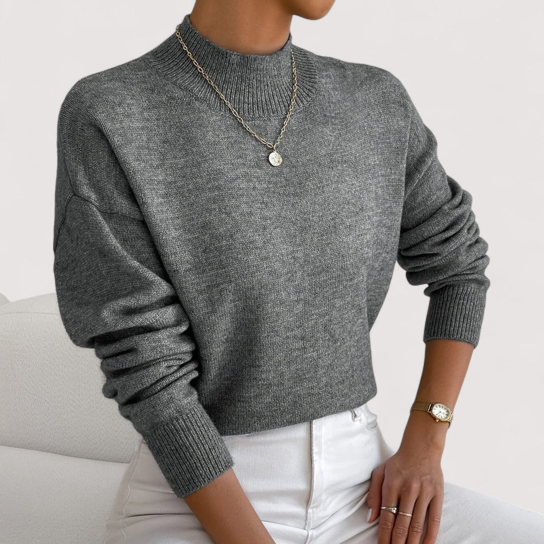 Model wearing a pink turtleneck sweater in a cozy home setting