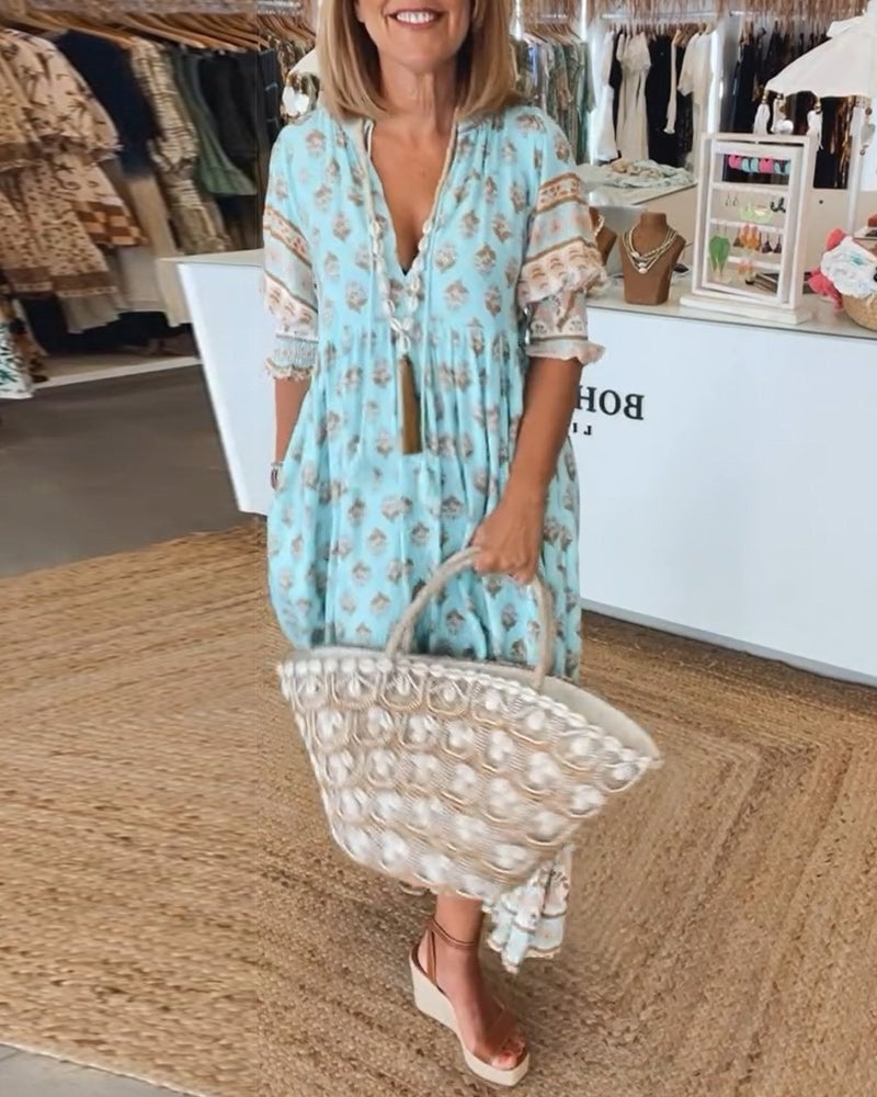 Woman wearing a flowing boho midi tassel dress in blue with relaxed silhouette and tassel hem detail