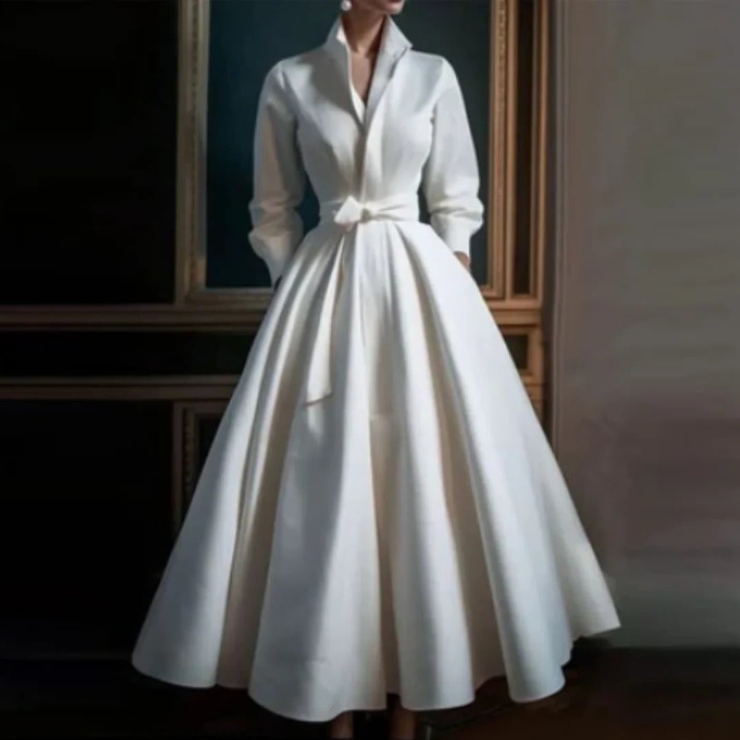 Woman wearing a white long sleeve V-neck A-line midi dress with a self-tie bow belt, front view