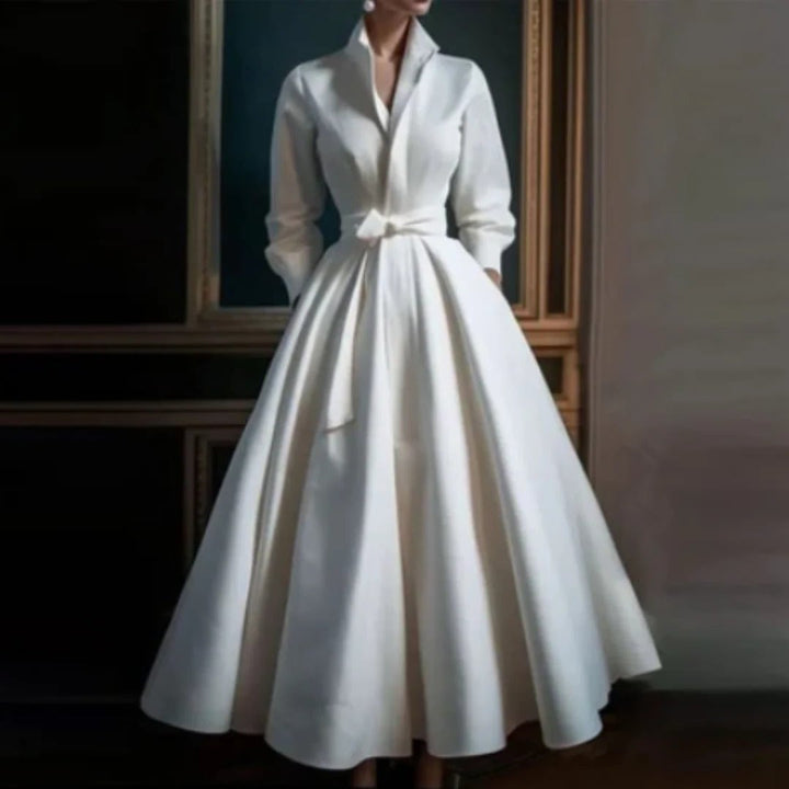 Woman wearing a white long sleeve V-neck A-line midi dress with a self-tie bow belt, front view