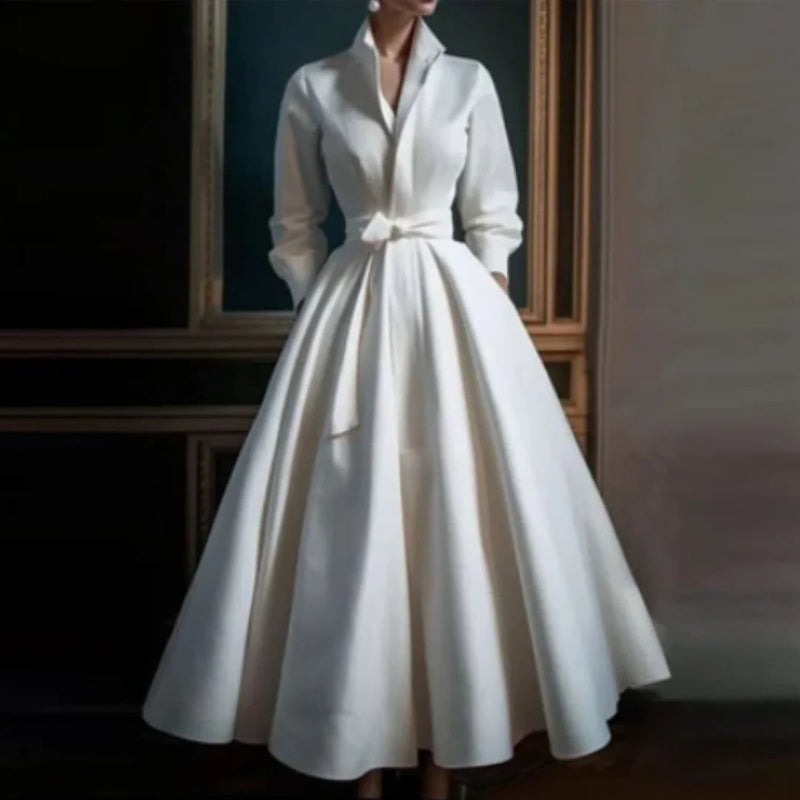 Woman wearing a white long sleeve V-neck A-line midi dress with a self-tie bow belt, front view