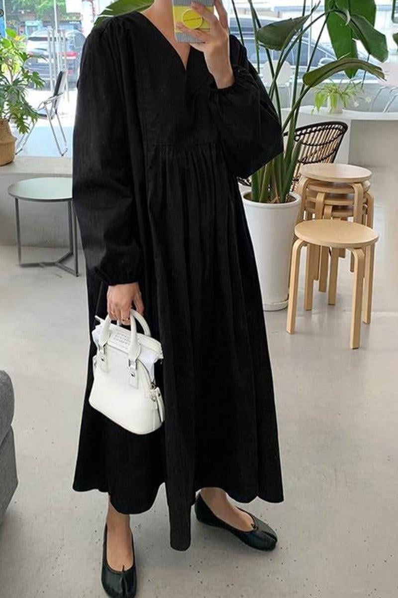Woman in a black v-neck smocked midi dress with puff sleeves, full-length front view