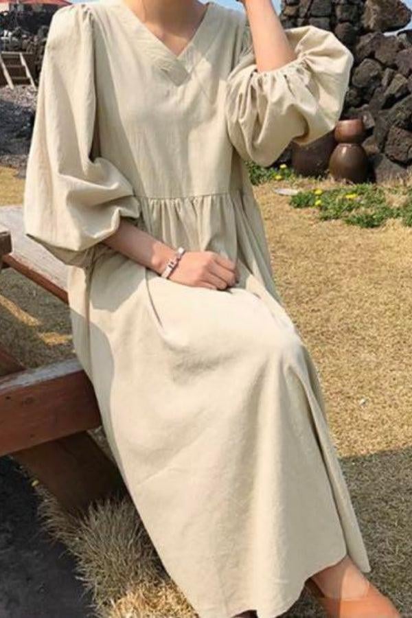 Woman wearing a white smocked waist v-neck midi dress with voluminous balloon sleeves