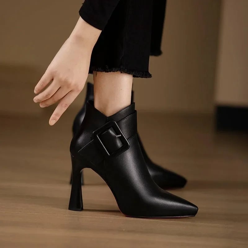 Aveline buckle heel boots in black showing sleek silhouette and buckle detail, side view