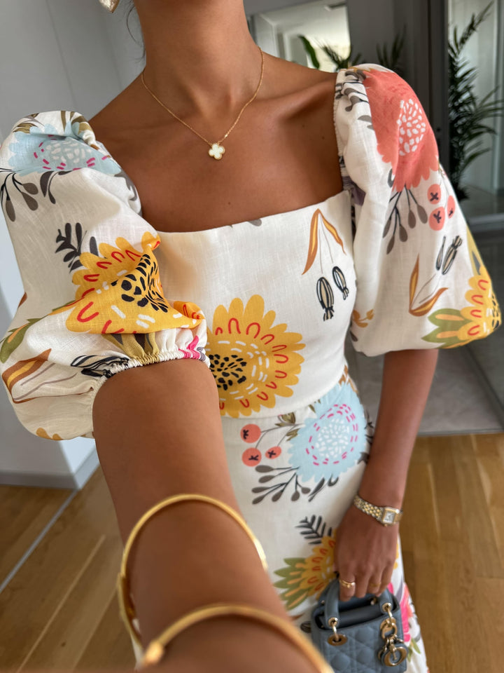 Side view of a woman in a multicolor floral midi dress with puff sleeves and ruffled hem