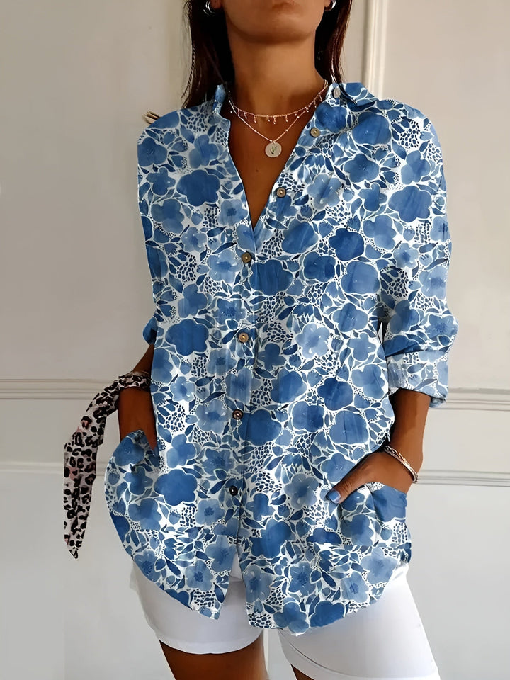 Woman wearing the Avril chic blouse in a vibrant floral print, styled with jeans for a casual daytime look