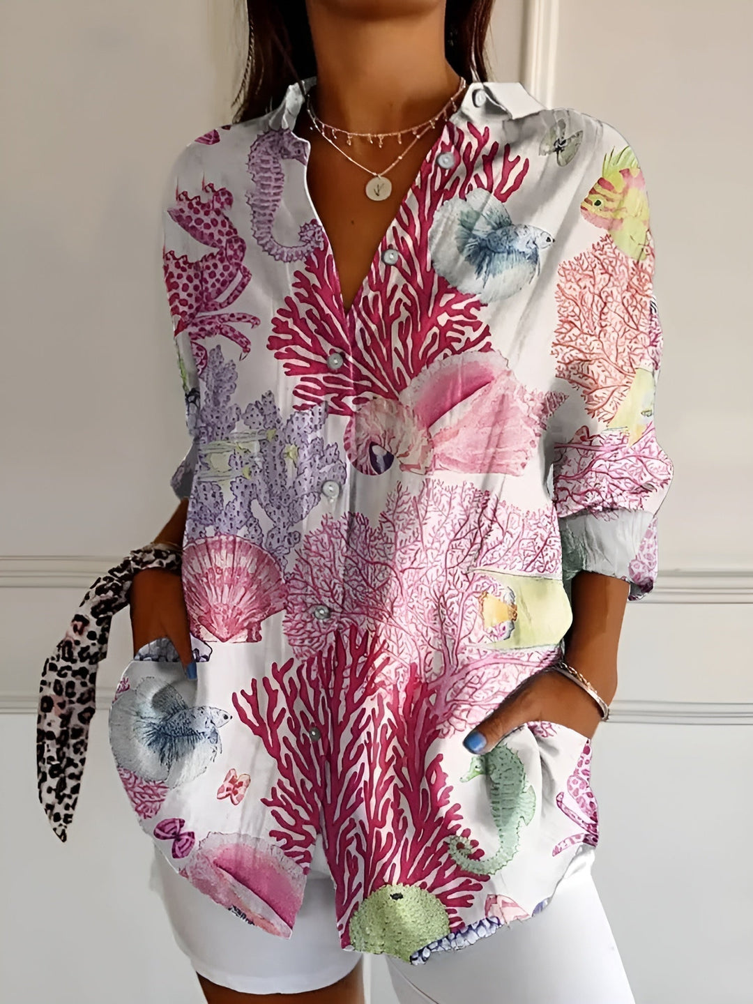 Model wearing the Avril blouse in pink floral print paired with a white skirt for a polished look