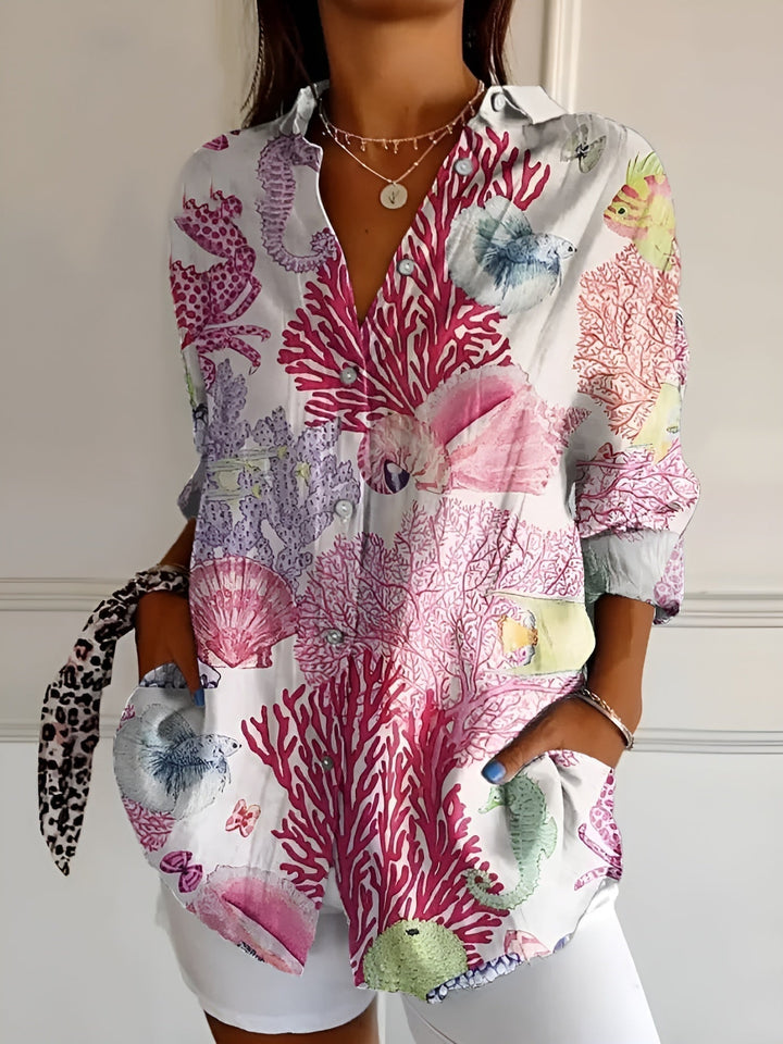 Model wearing the Avril blouse in pink floral print paired with a white skirt for a polished look