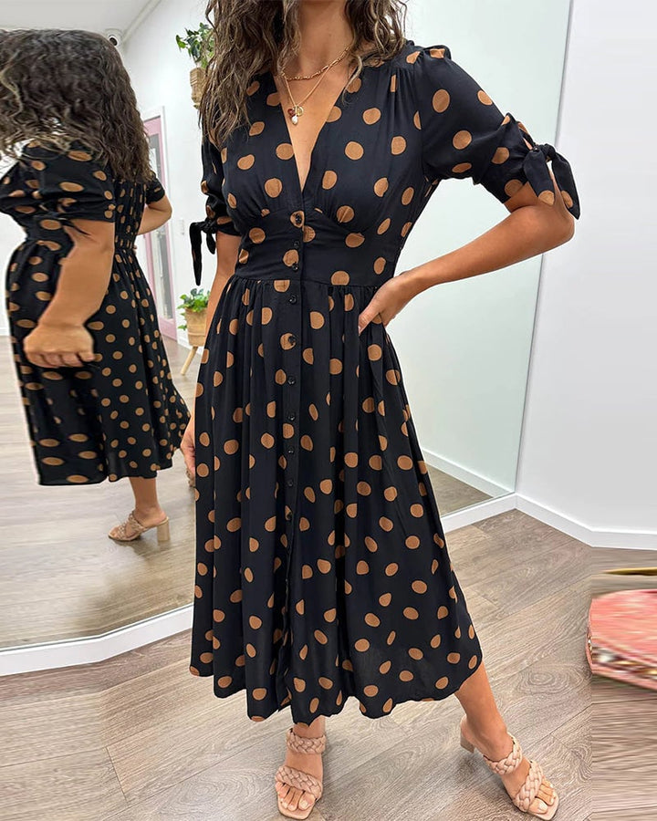 Woman wearing a black polka dot V-neck midi dress with button front closure