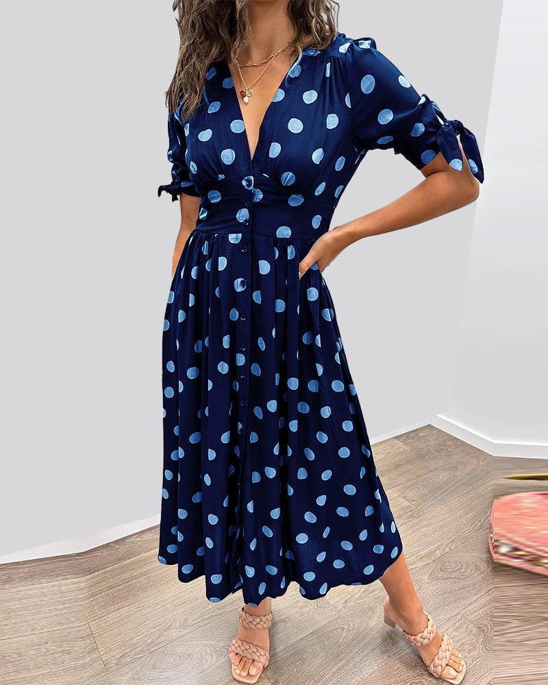 Woman wearing a dark blue polka dot V-neck midi dress with button front closure