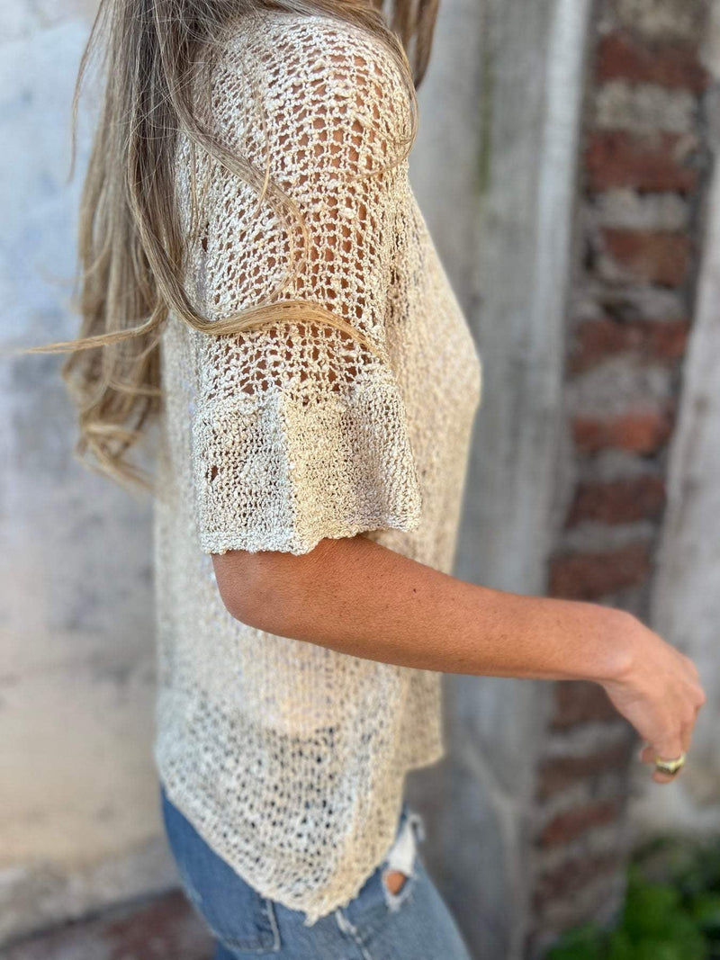 Woman in a white textured knit top styled with tailored pants, showcasing a polished everyday look